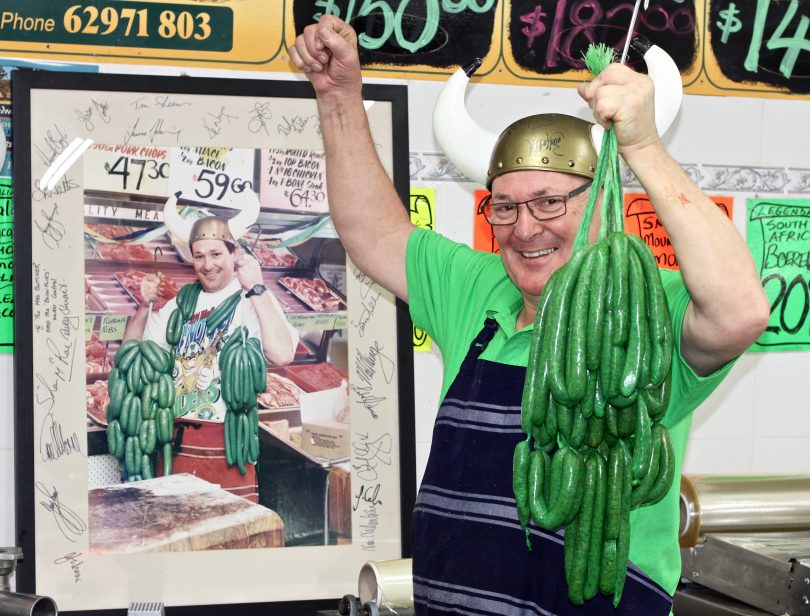 Butcher holding up green sausages