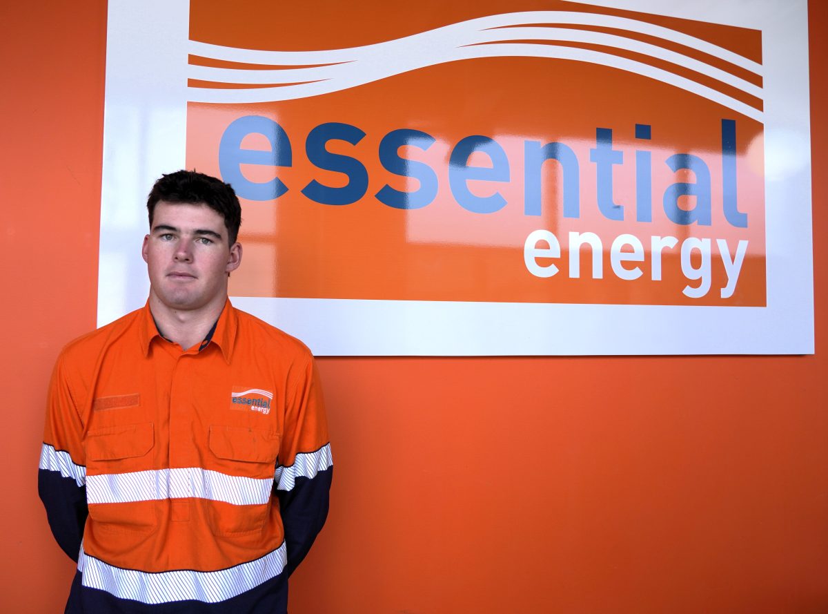 Man in orange standing in front of Essential Energy sign