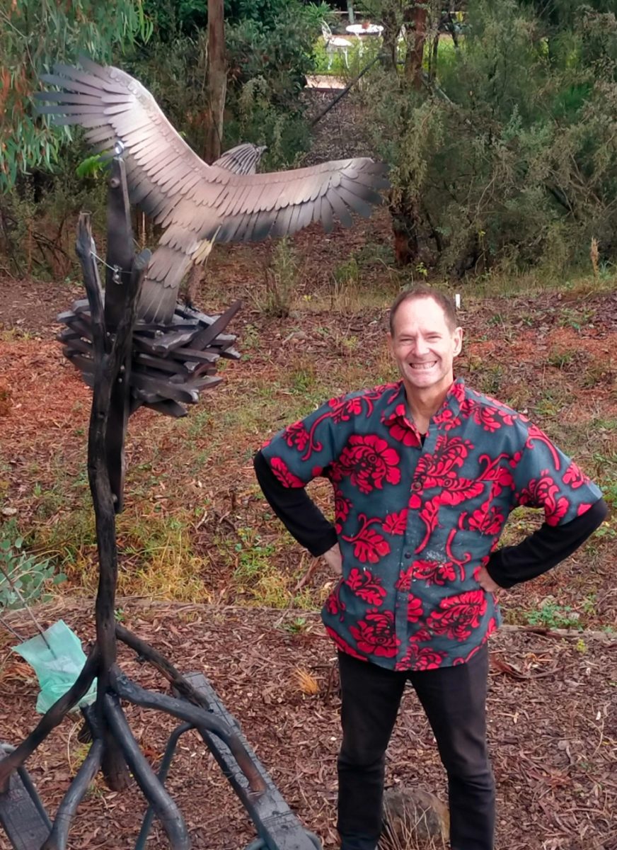 Man in loud shirt in front of sculpture of eagle