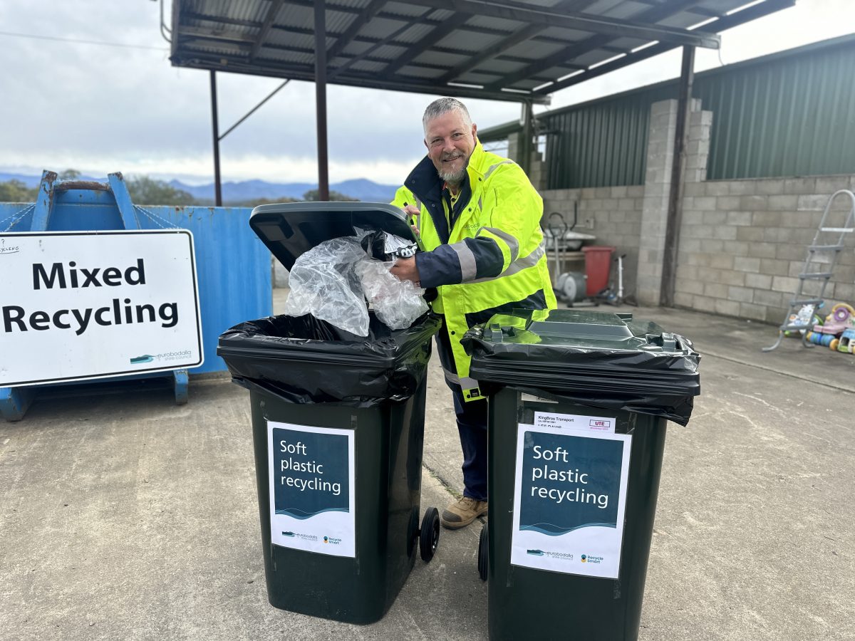 A man standing in front of two recycling bins