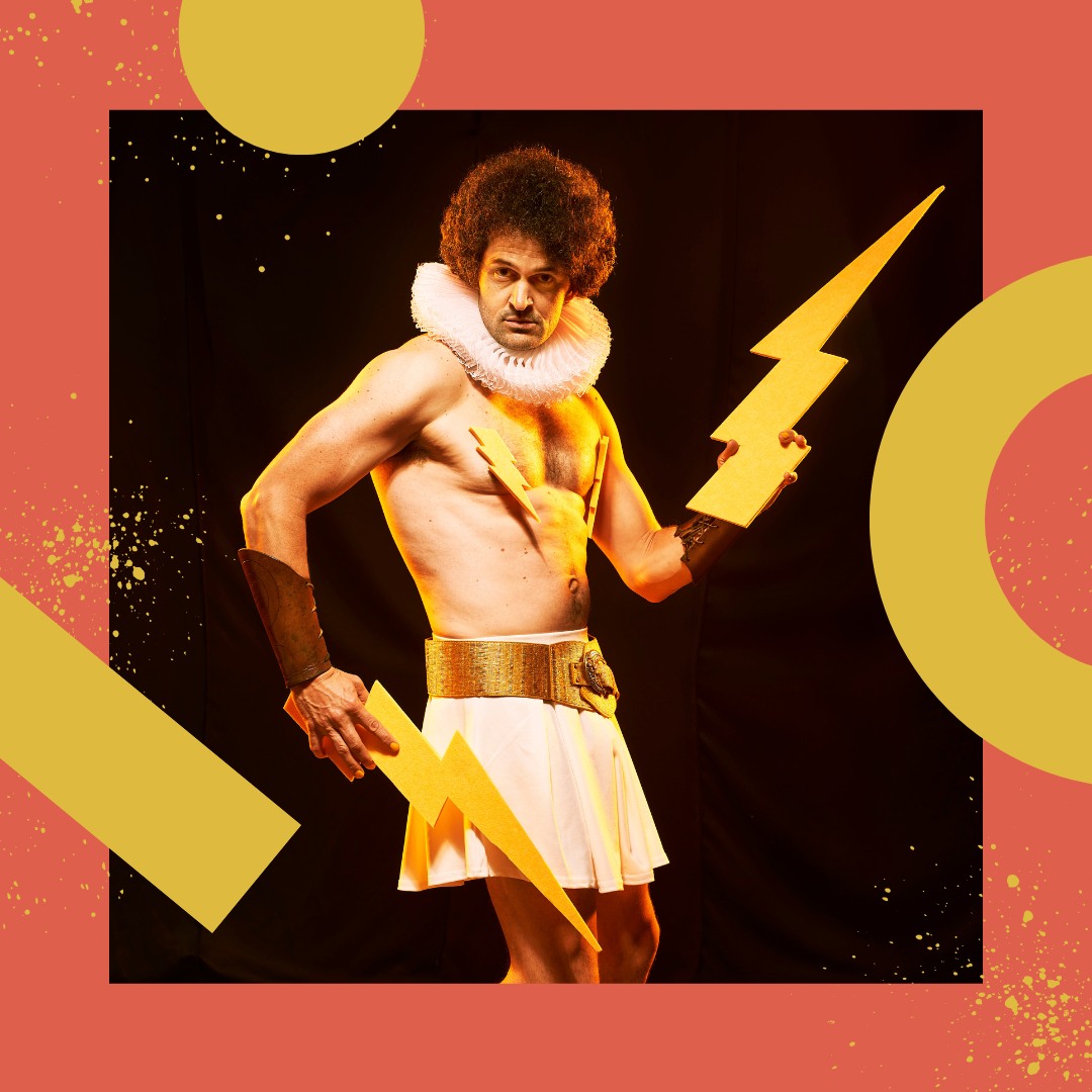 A man in a theatre costume holding lightning bolt props