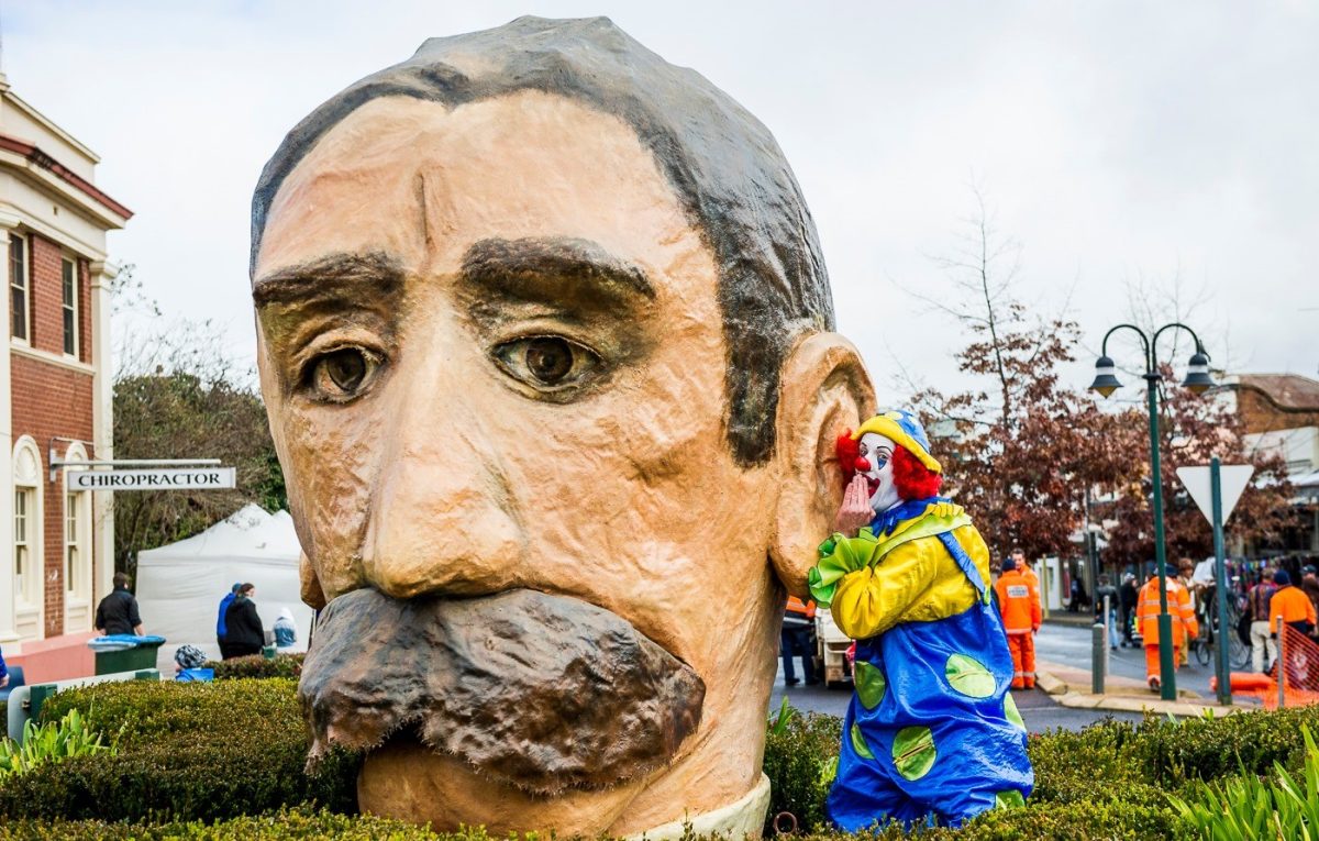 A clown whispering into the ear of a large head