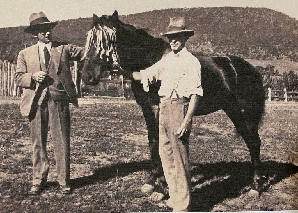 old photo of two men and a horse in a rural paddock
