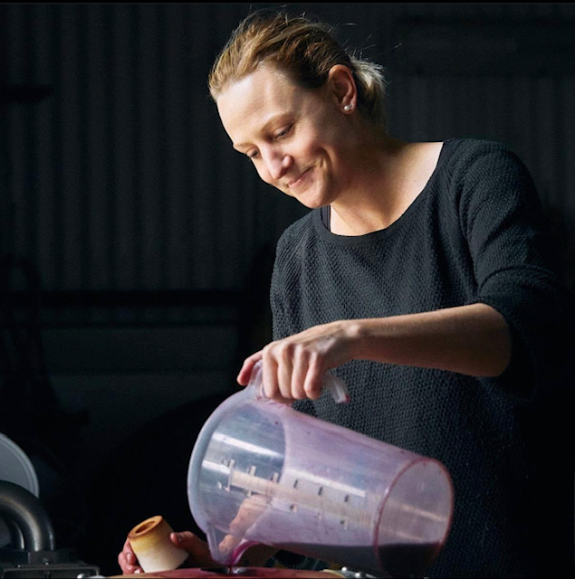 A woman pouring wine from a large plastic jug