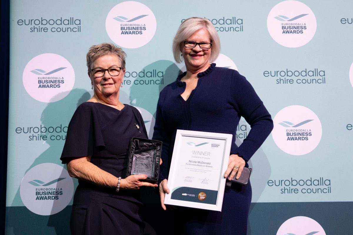 Two people in formal dress holding awards