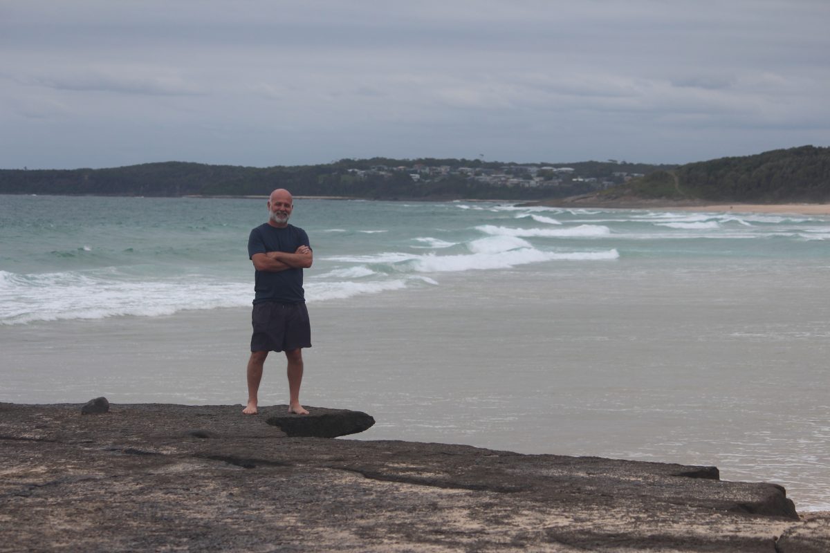 Man standing on rocks in front of surf