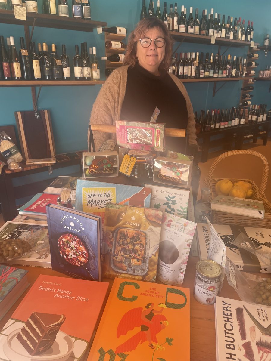 Woman behind display of cookbooks with wine in background