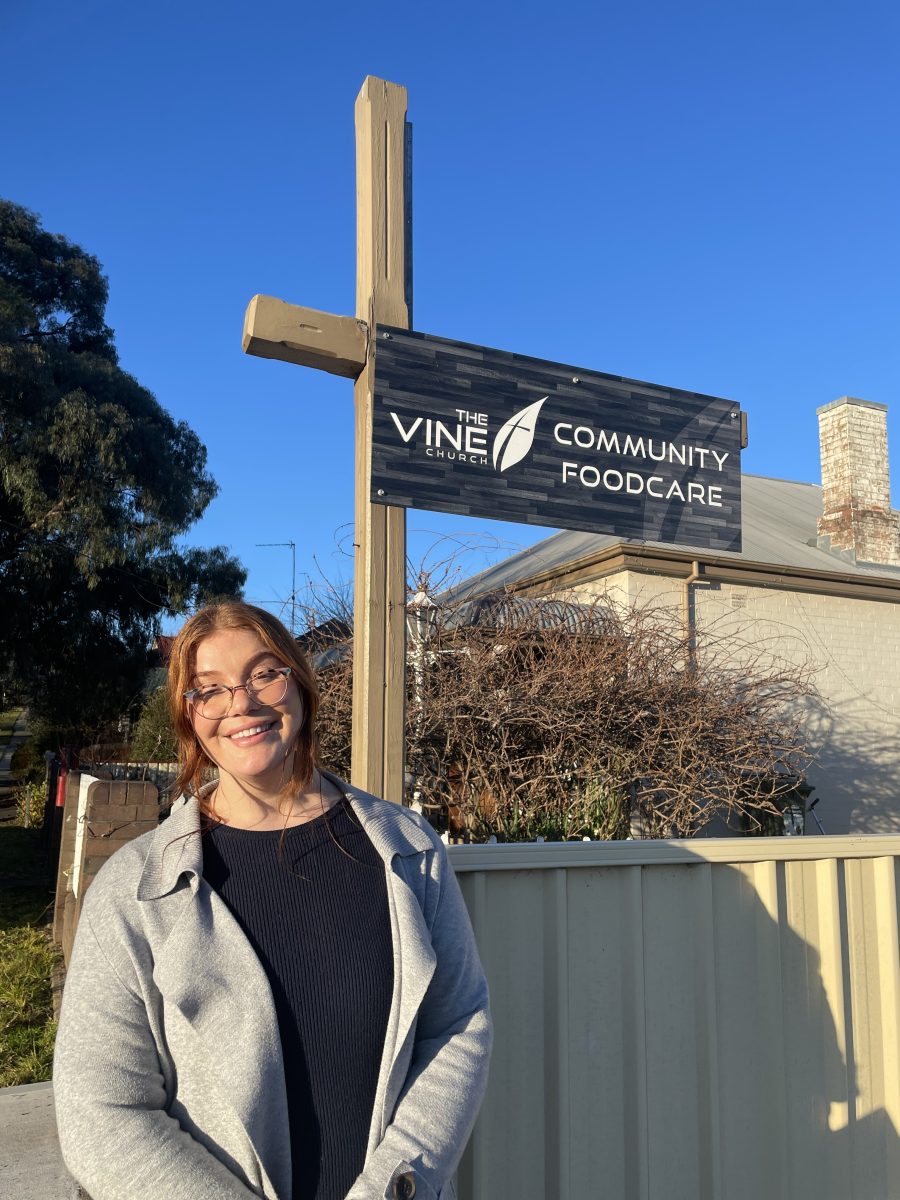 woman in front of sign that says vine community foodcare