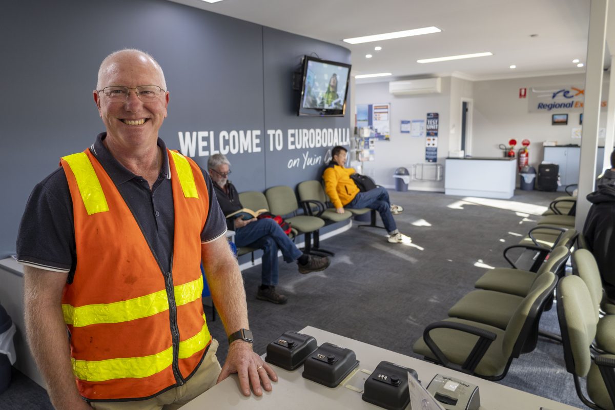 A man in a high-vis vest standing inside an airport terminal