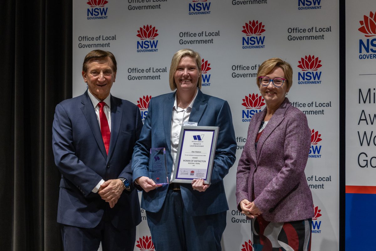 Woman holding plaque in between man and another woman.