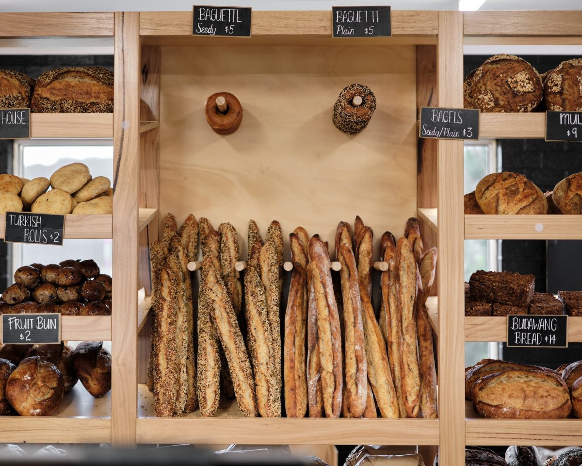 Wooden racks with baguettes, bagels and sourdough loaves.