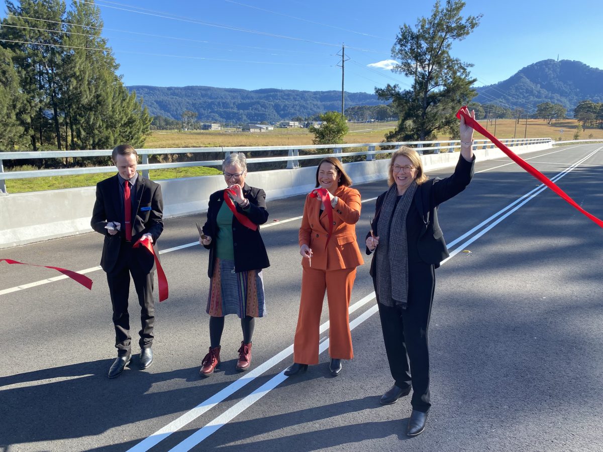 Four people standing in a line holding bits of cut red ribbon