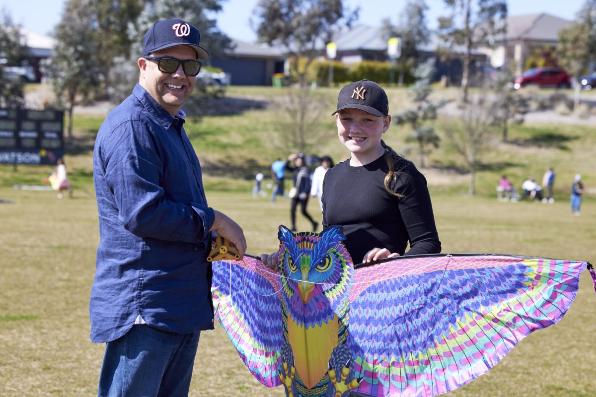 A man and girl holding a kite in the sun