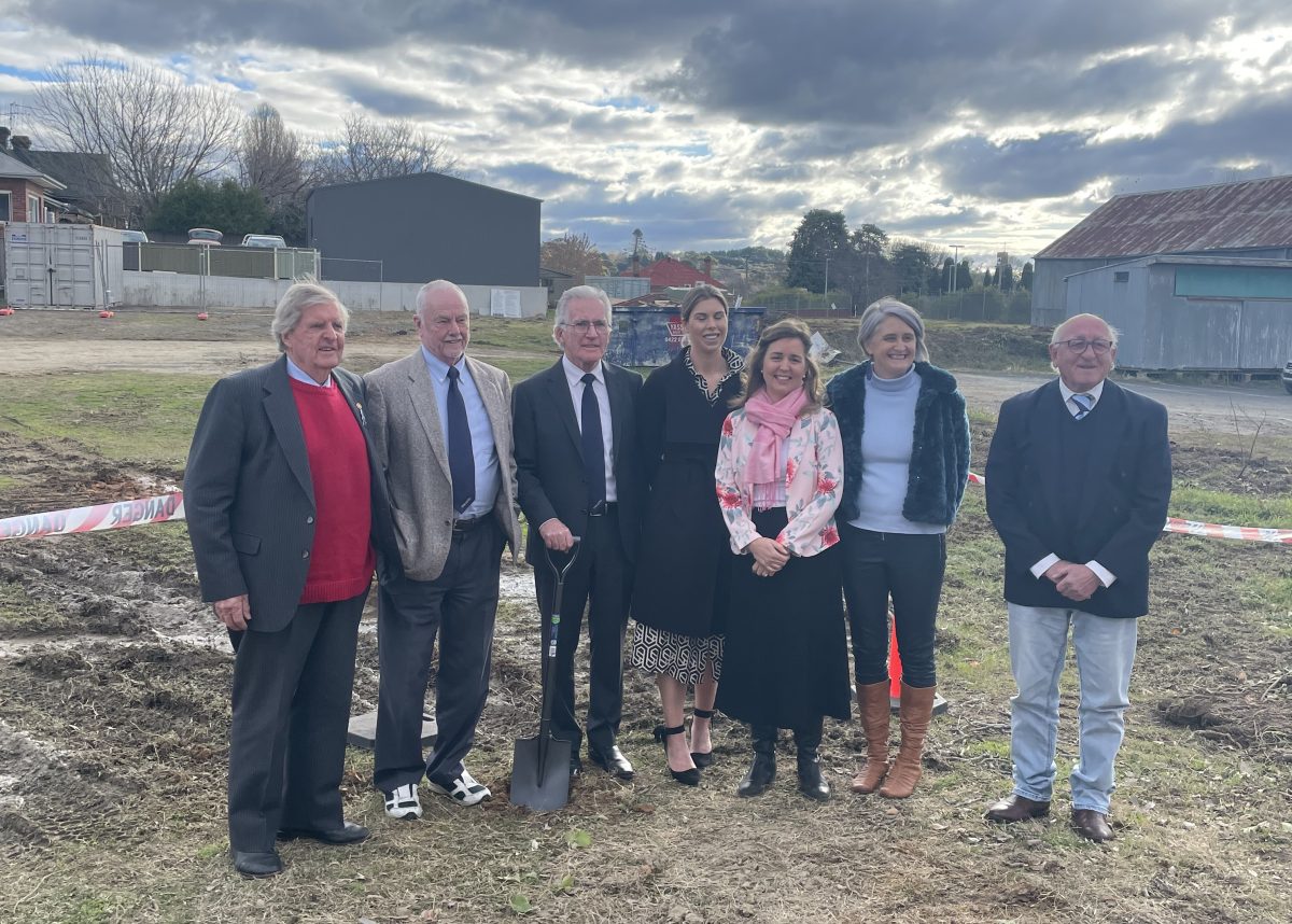 Seven people standing on vacant block for sod-turning ceremony