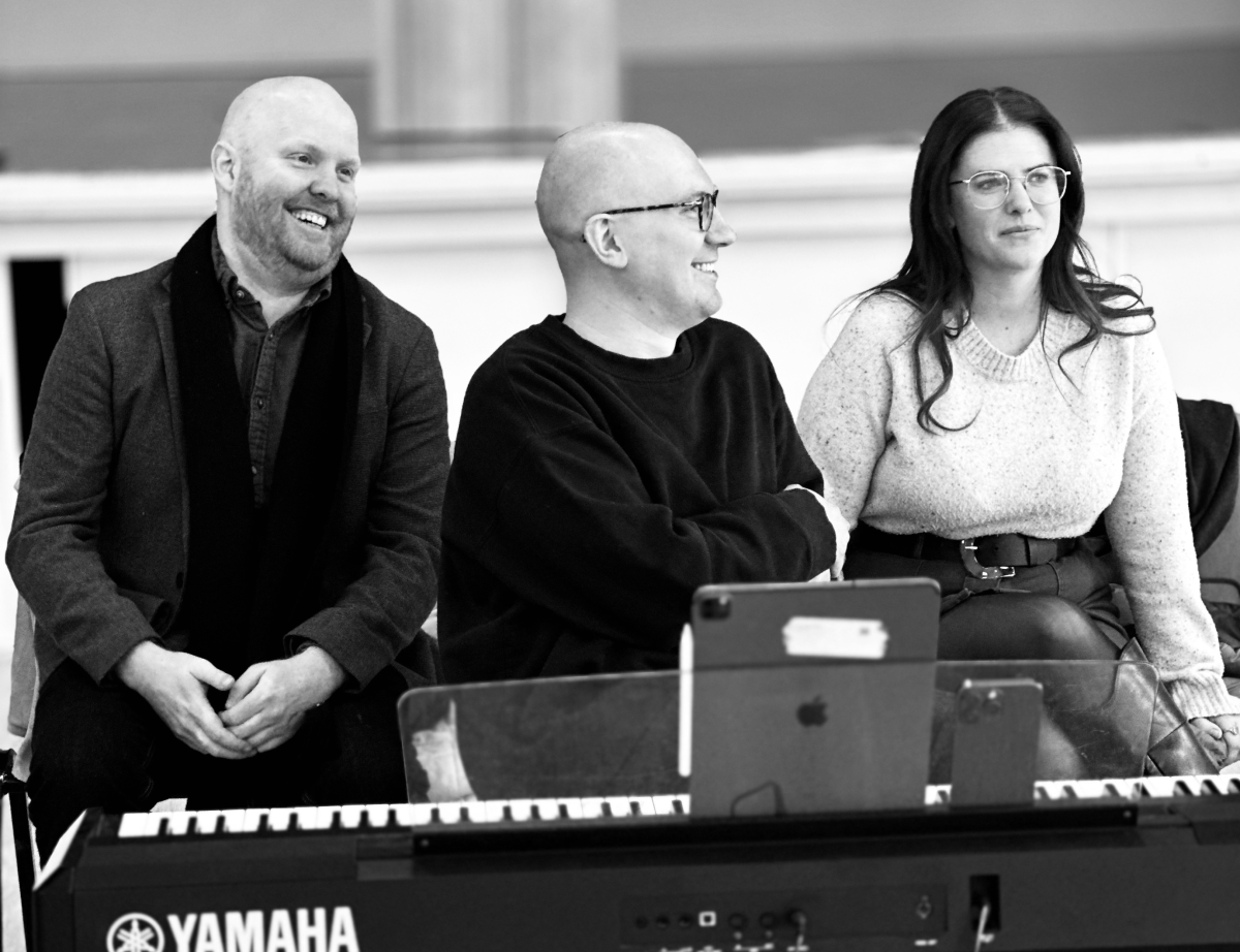 Three people sitting behind keyboard player.