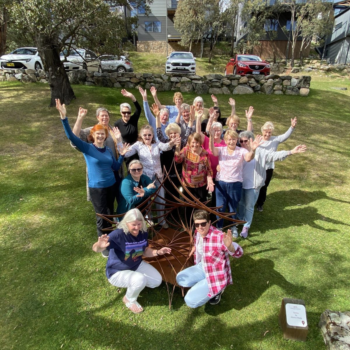 A group of people in a park, arms raised and smiling