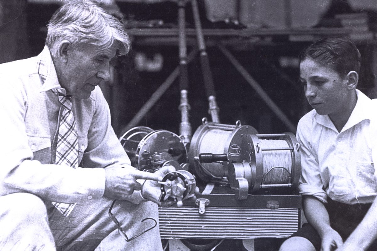 vintage photo of an old man explaining how a fishing reel works to a young boy