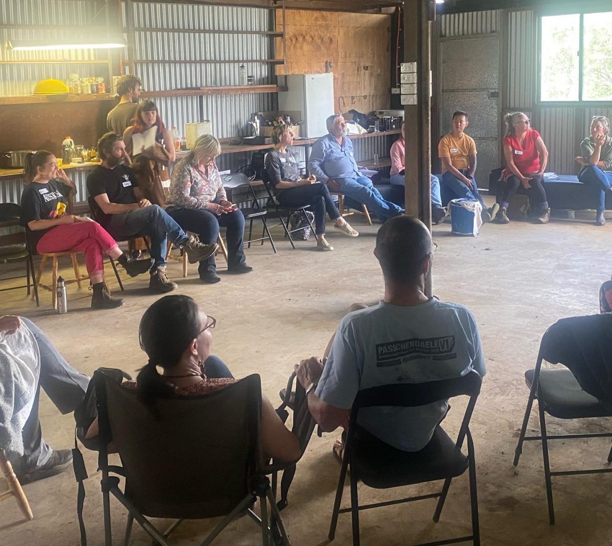 Circle of people on chairs talking together in a shed.