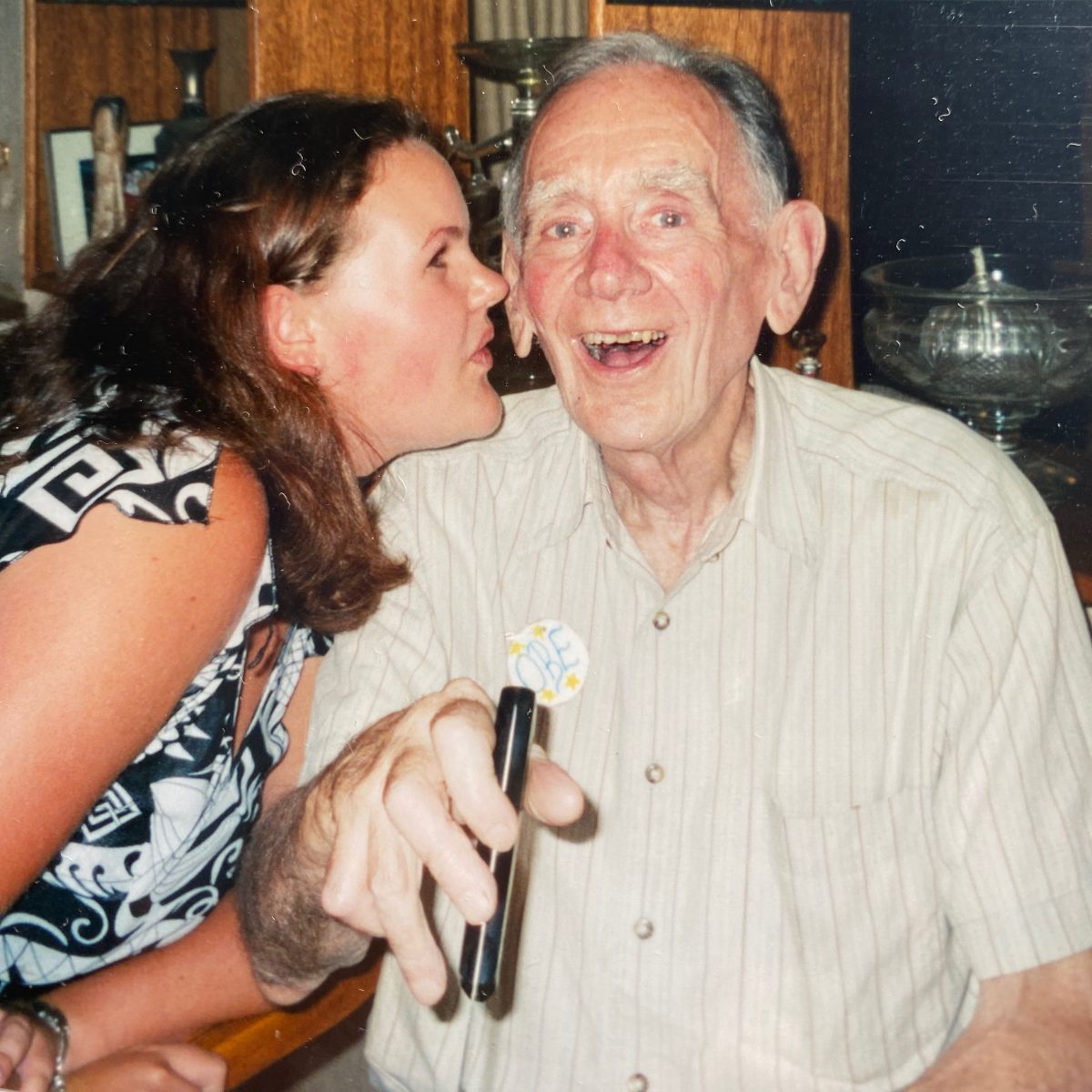 man being kissed by his granddaughter while he cuts his birthday cake