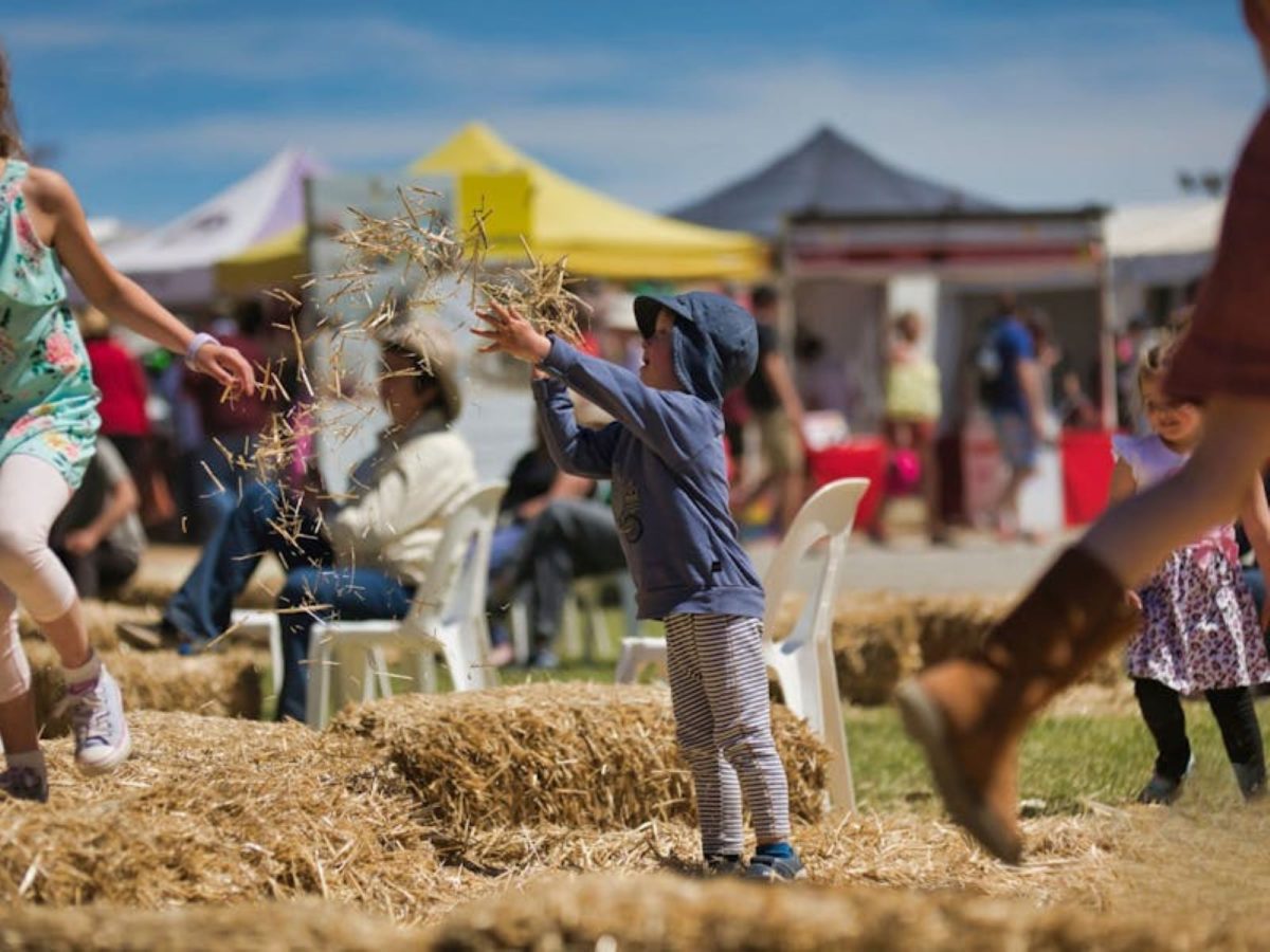 A child throwing hay in the air at Murrumbateman Field Days.