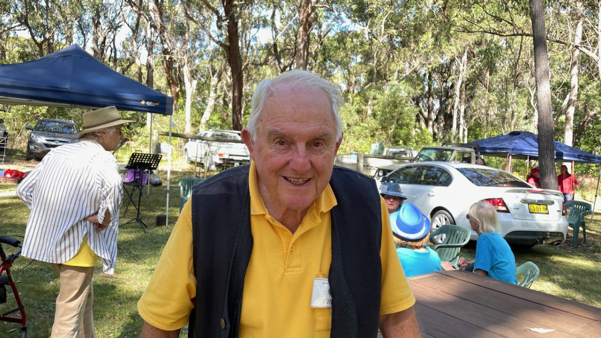 An elderly man in a yellow shirt and vest