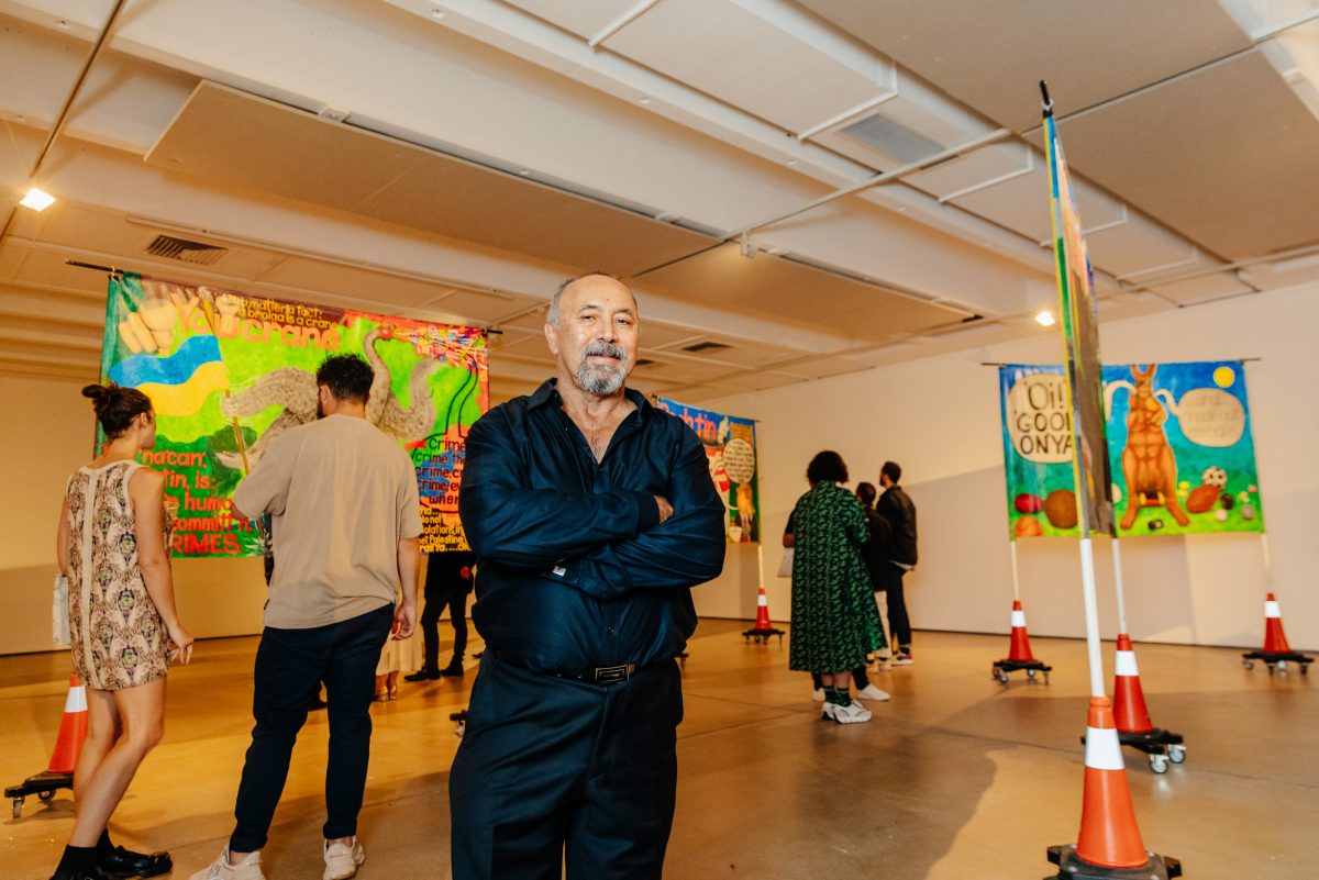 A man standing with his arms crossed in an art exhibition 