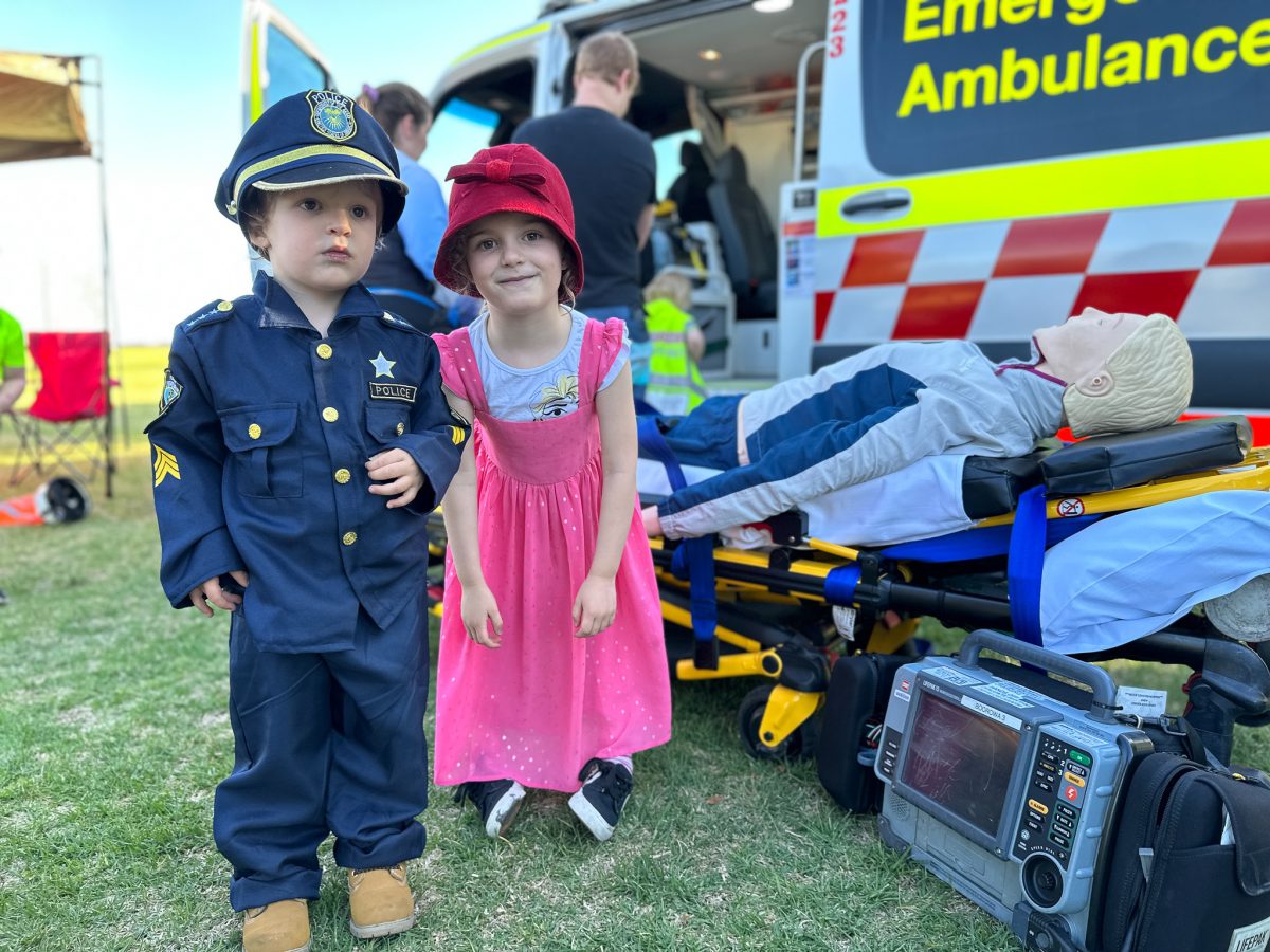 Kids playing dress-ups next to a doll on a stretcher