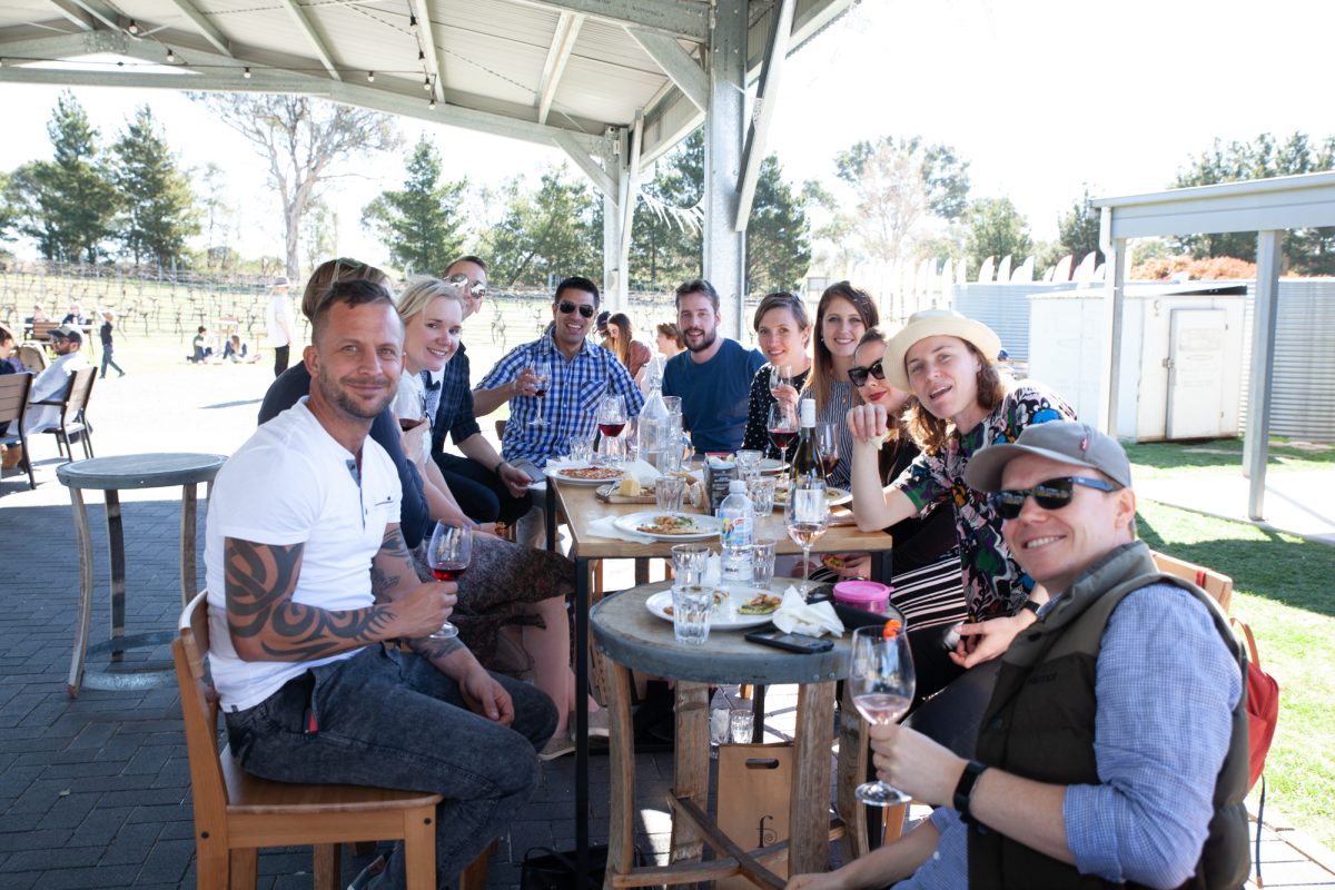 Long table of people dining and drinking wine