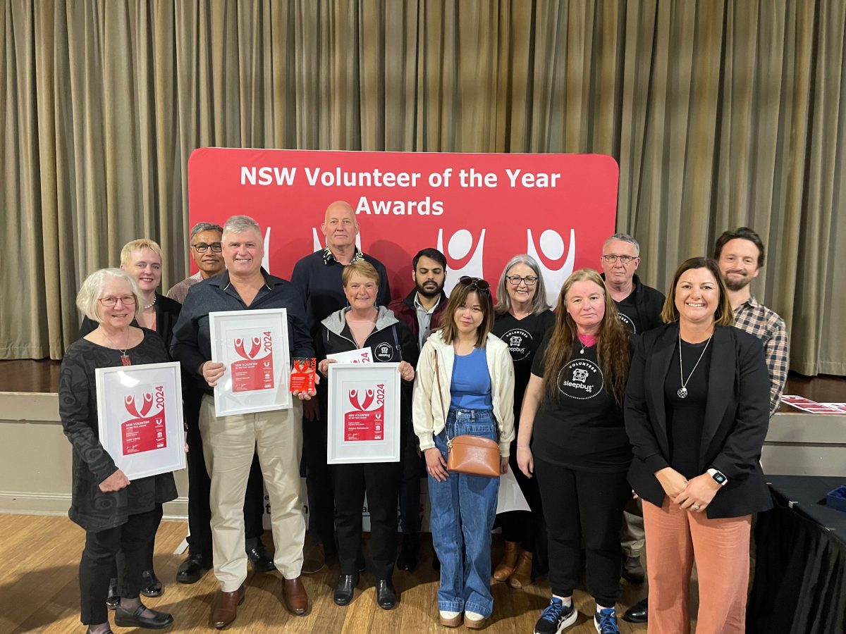 Group of people in front of NSW Volunteers of the Year Awards sign. 