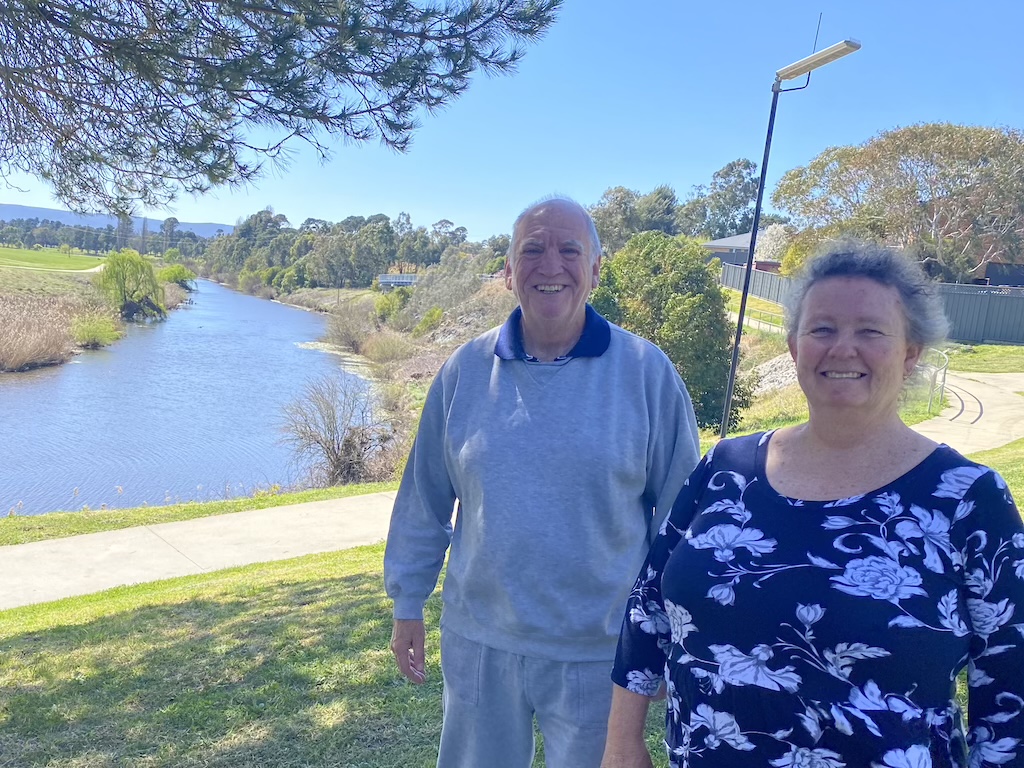 a man and a woman standing under a tree near a river