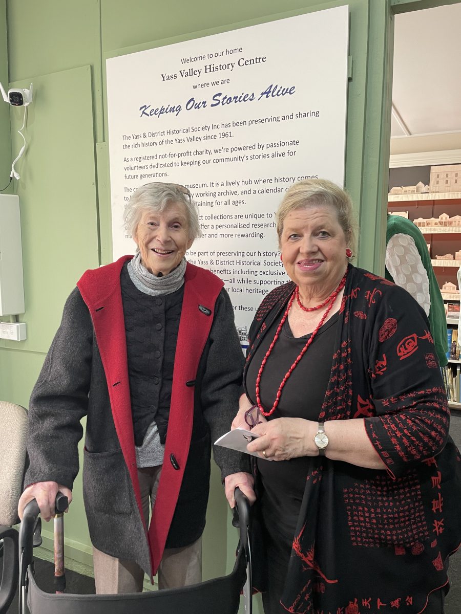 Two women in front of a sign headed: Keeping Our Stories Alive 