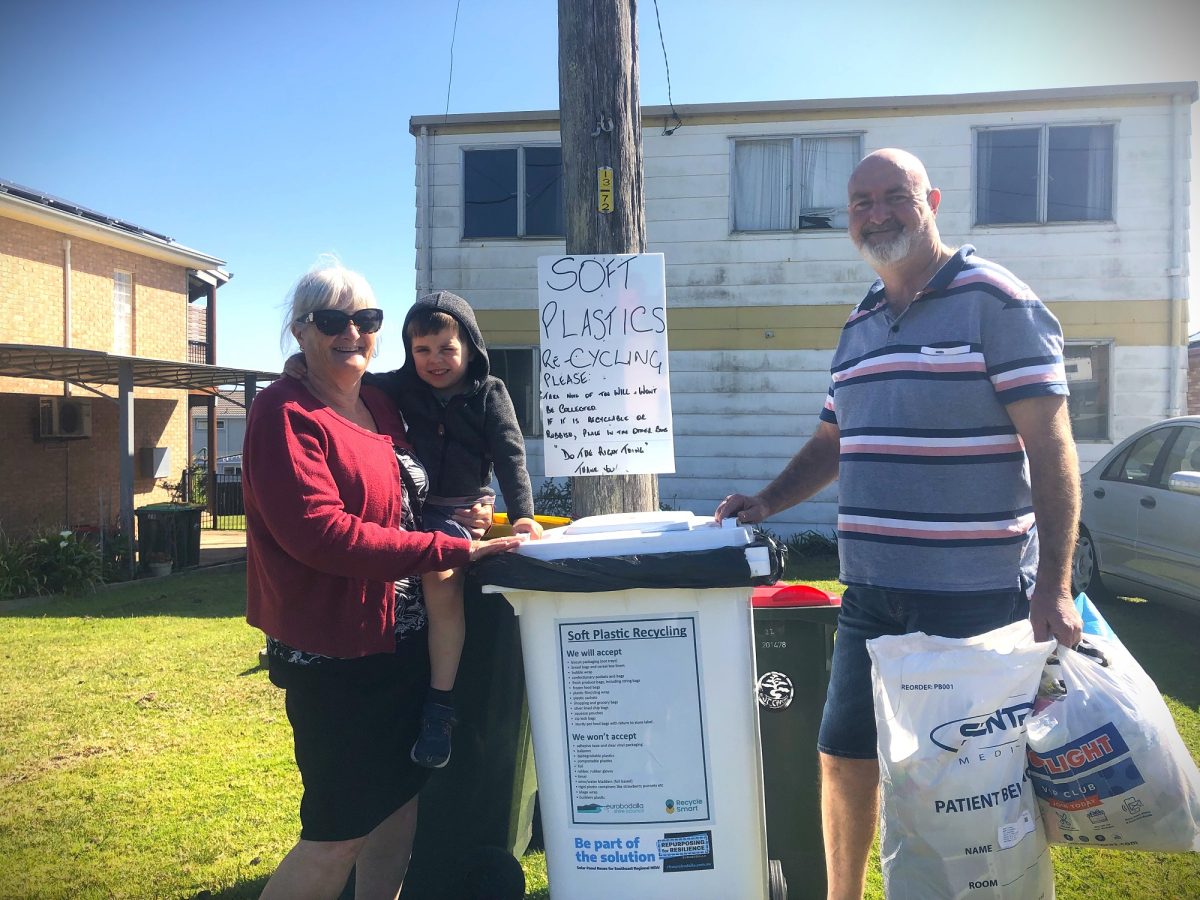 three people with a recycling bin