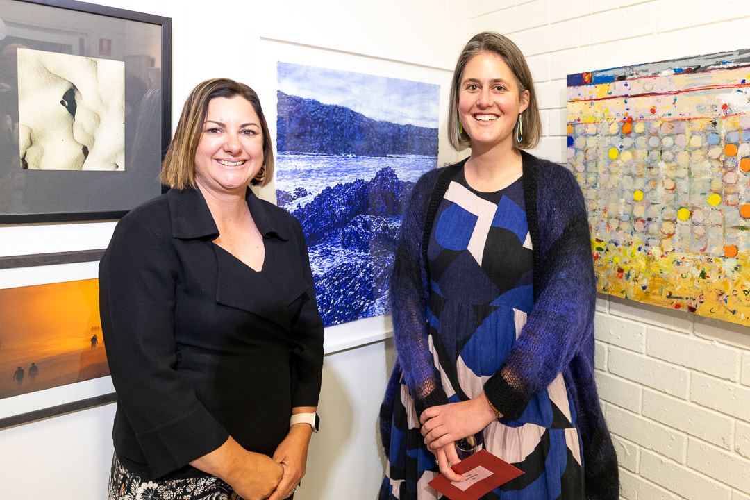 Two women standing before artwork