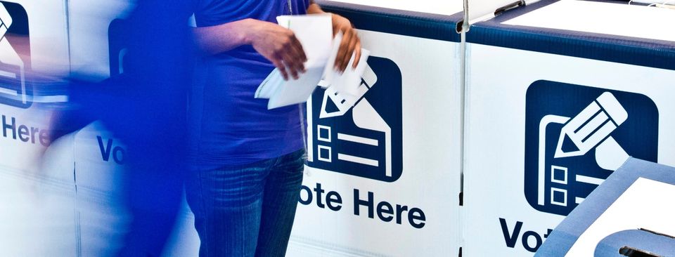 person with ballot papers at polling booth