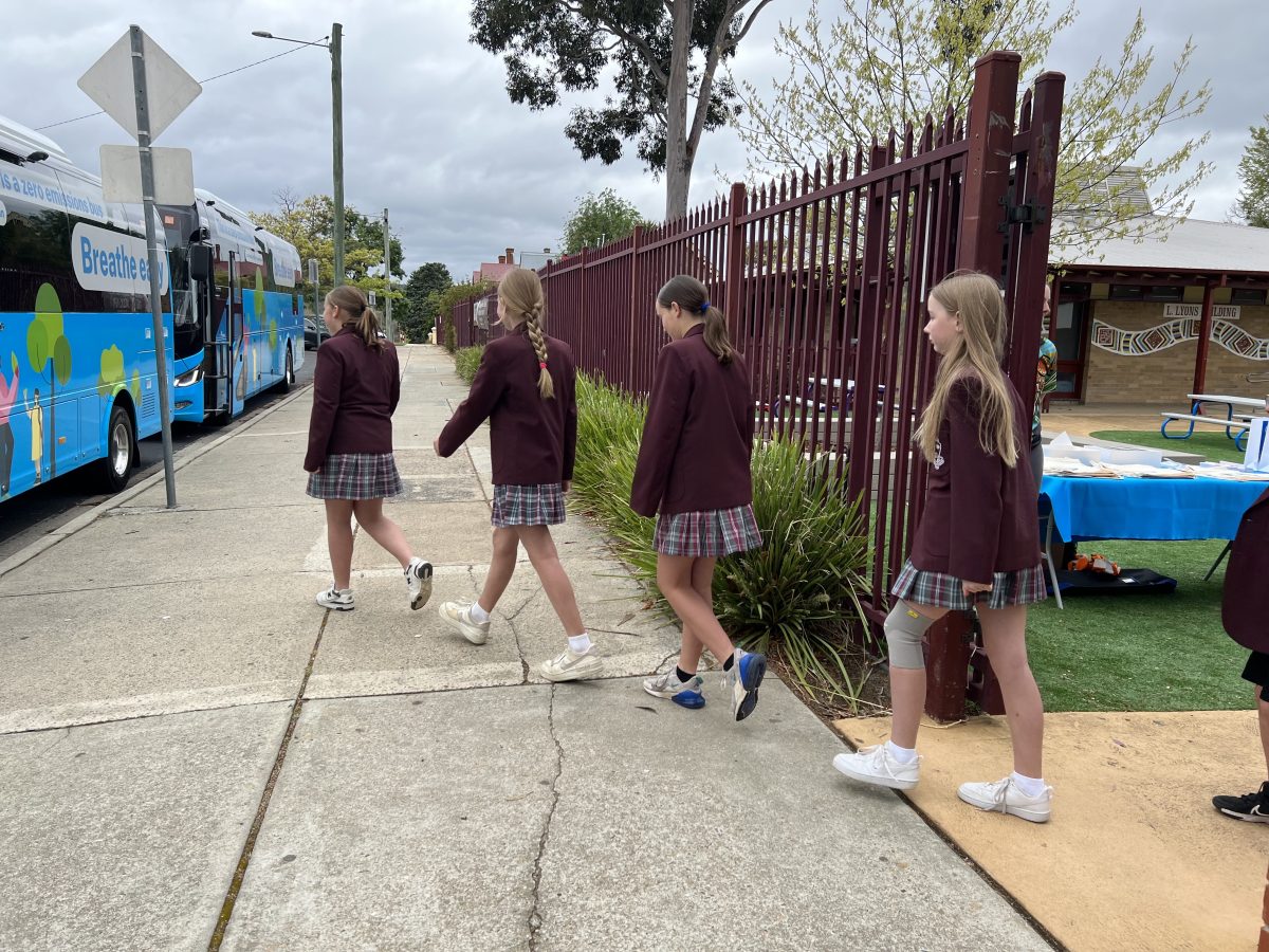 Students in school uniform walking in a line to the bus