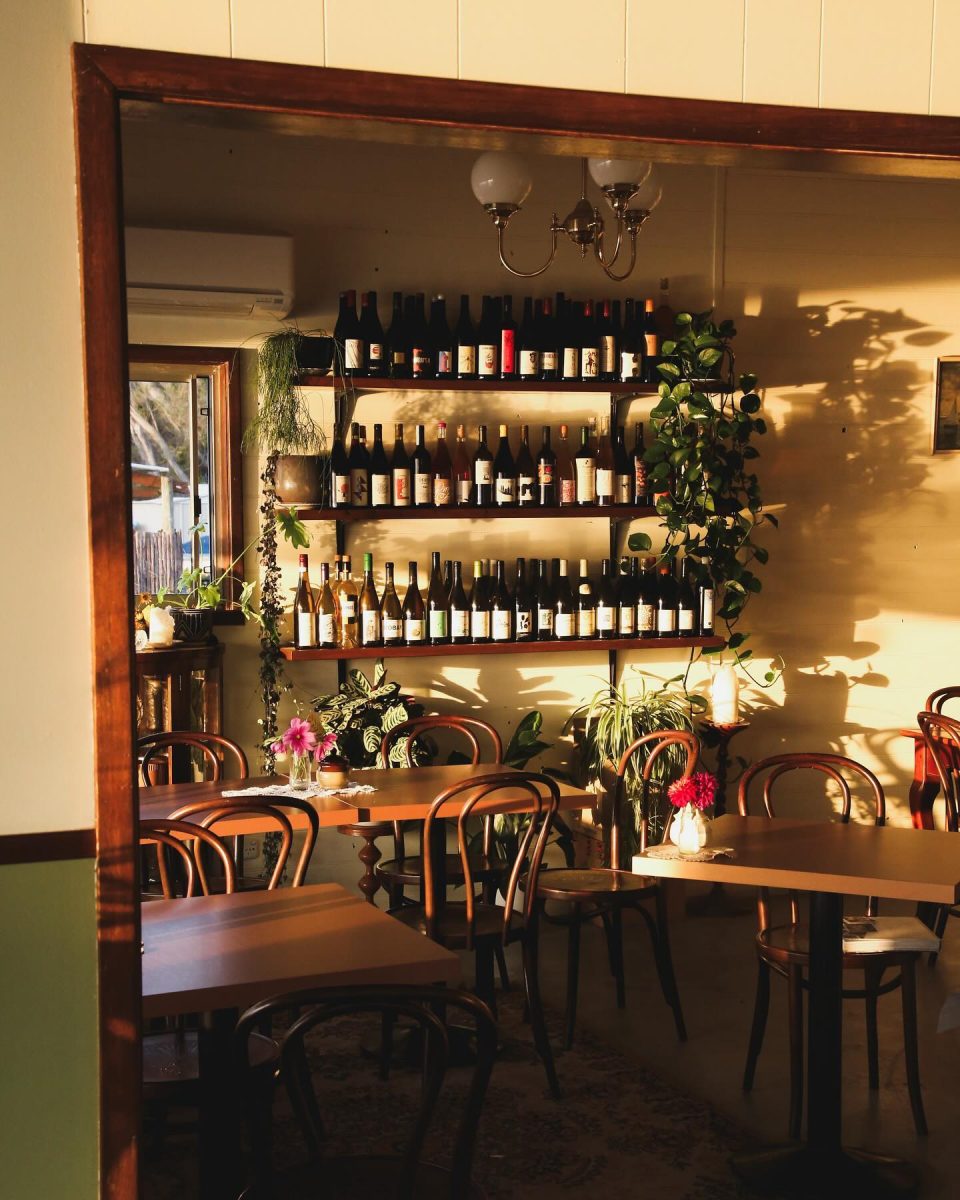 Sunset shot of cafe interior with a shelf of wine bottles.