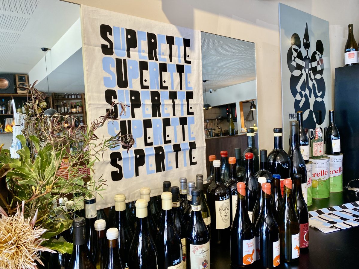 A teatowel reading Superette with bottles of wine