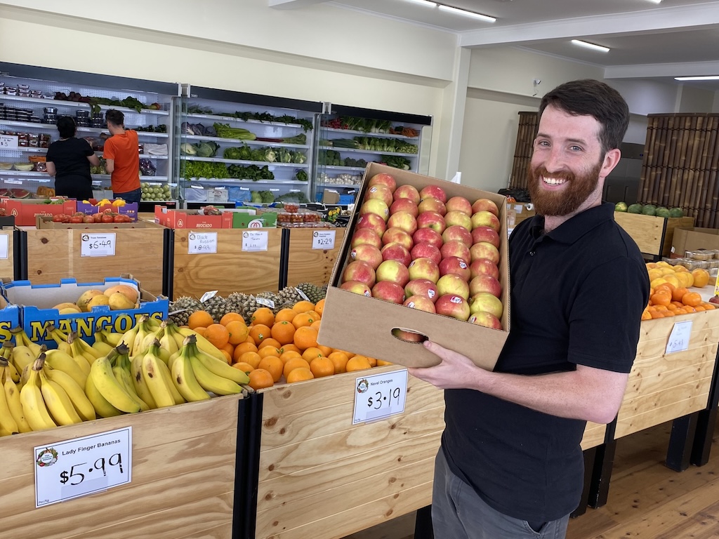 a man holding a tray of apples in a fruit shop