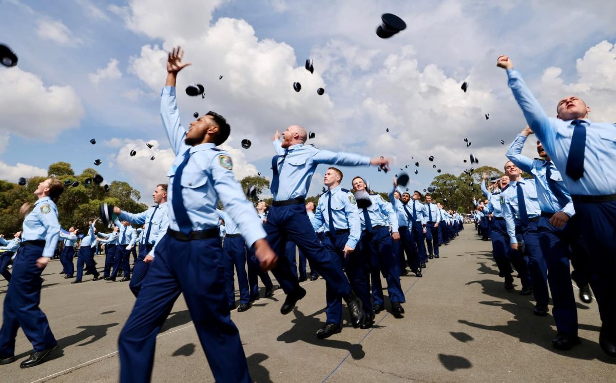 police probationary constables throw their hats into the air at their graduation ceremony