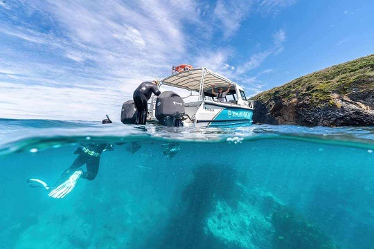 Two divers climbing into a small boat while on the water