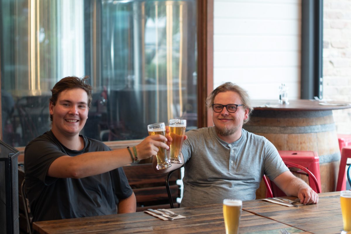 two young men toasting with beers in a brewery