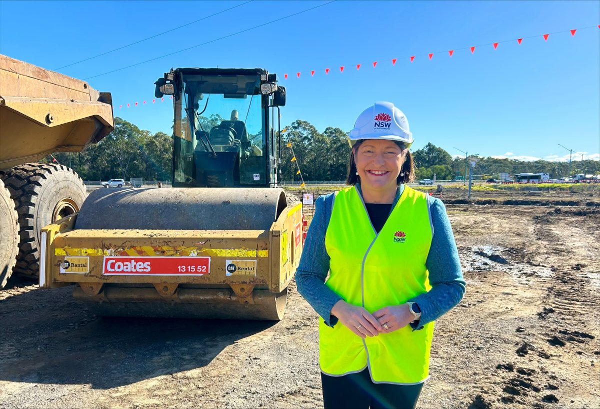 A woman in a hard hat and high-vis vest standing at a construction site