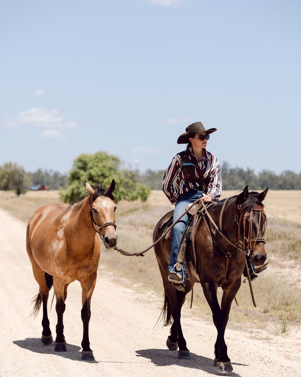 A woman riding one horse while leading another 