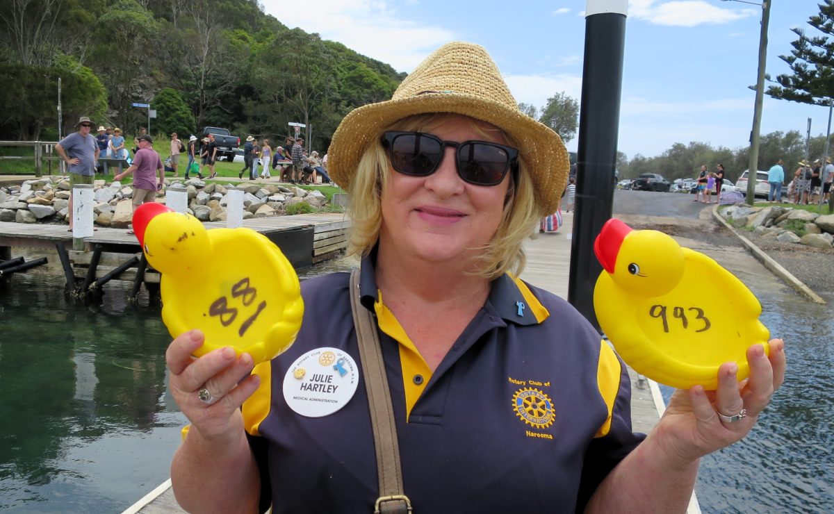 A woman holding up two yellow plastic ducks with a number written on each