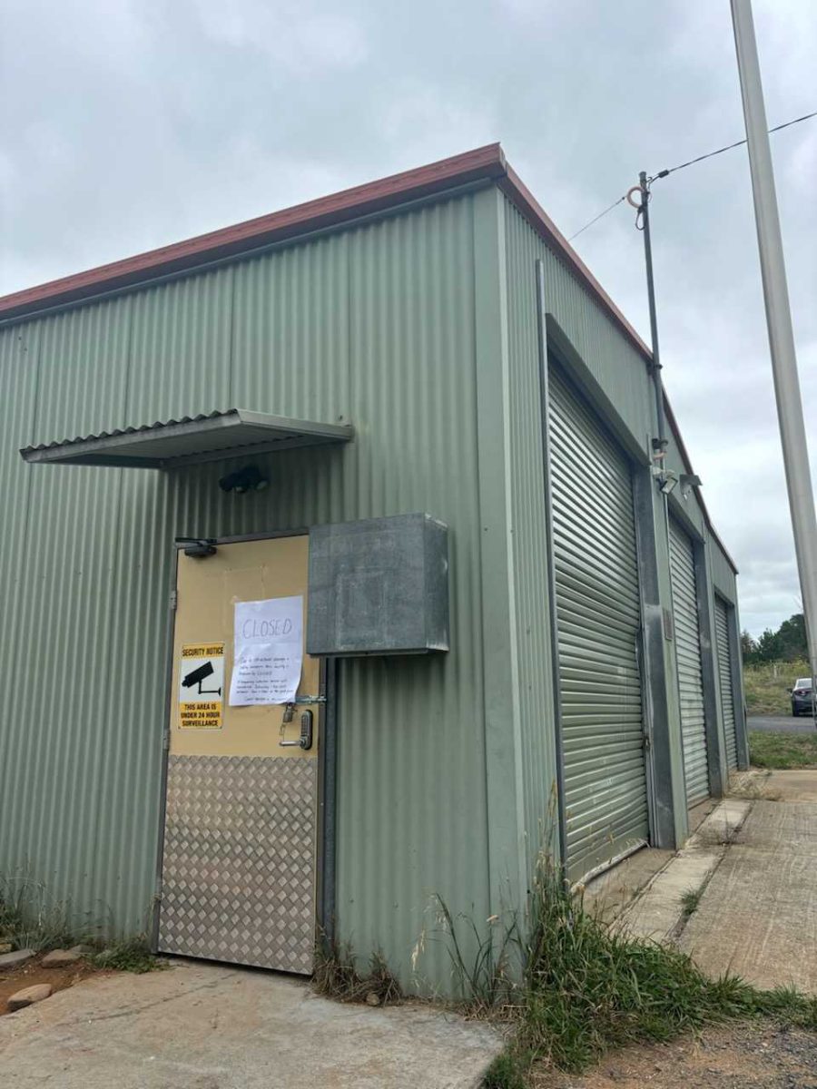 The side of a green shed with a ''Closed'' sign on a door