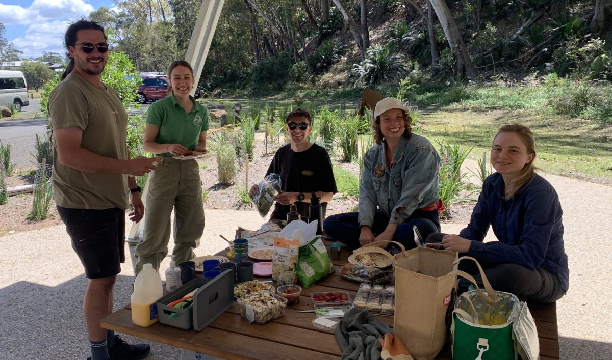 Some Intrepid Landcare volunteers enjoying a picnic as part of a working bee at Maloneys Beach in October 2024. 