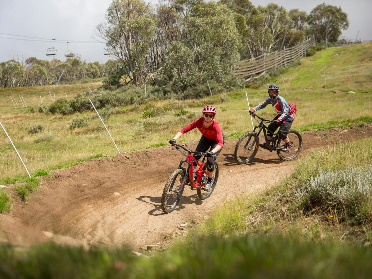 a photo of women mountain biking down a banked turn