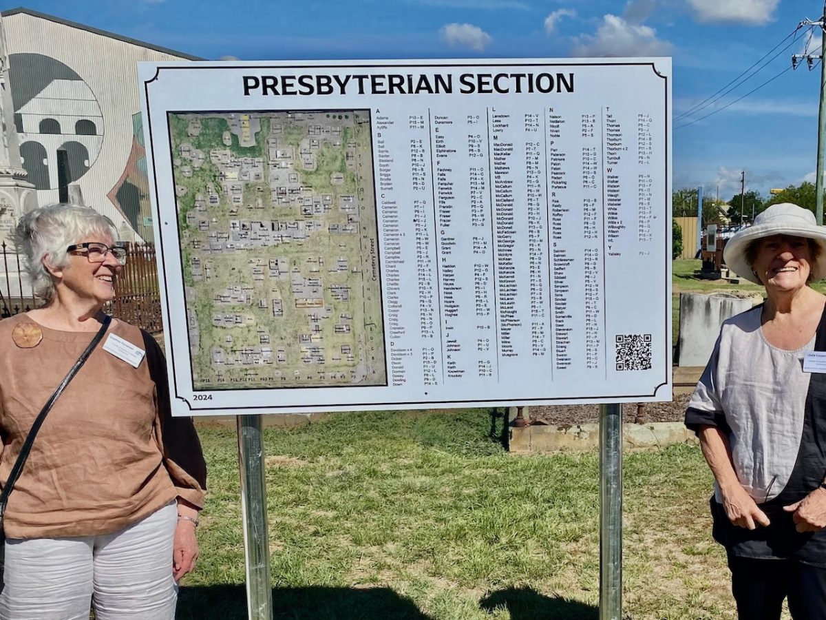 two women and a sign at a cemetery