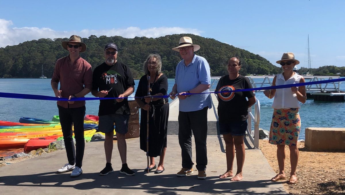 Eurobodalla Shire Mayor Mat Hatcher, Joonga Land and Water Aboriginal Corporation director Wally Stewart, Aunty Vivienne Mason of the Djaadjawan Dancers, Member for Bega Dr Michael Holland, Julie-Ann Mason, chair of Wagonga Local Aboriginal Land Council, and Tonia Clarkson of NSW Department of Primary Industries and Regional Development, cutting the ribbon at the official opening of the Wagonga Inlet Living Shoreline in Narooma on 1 February.