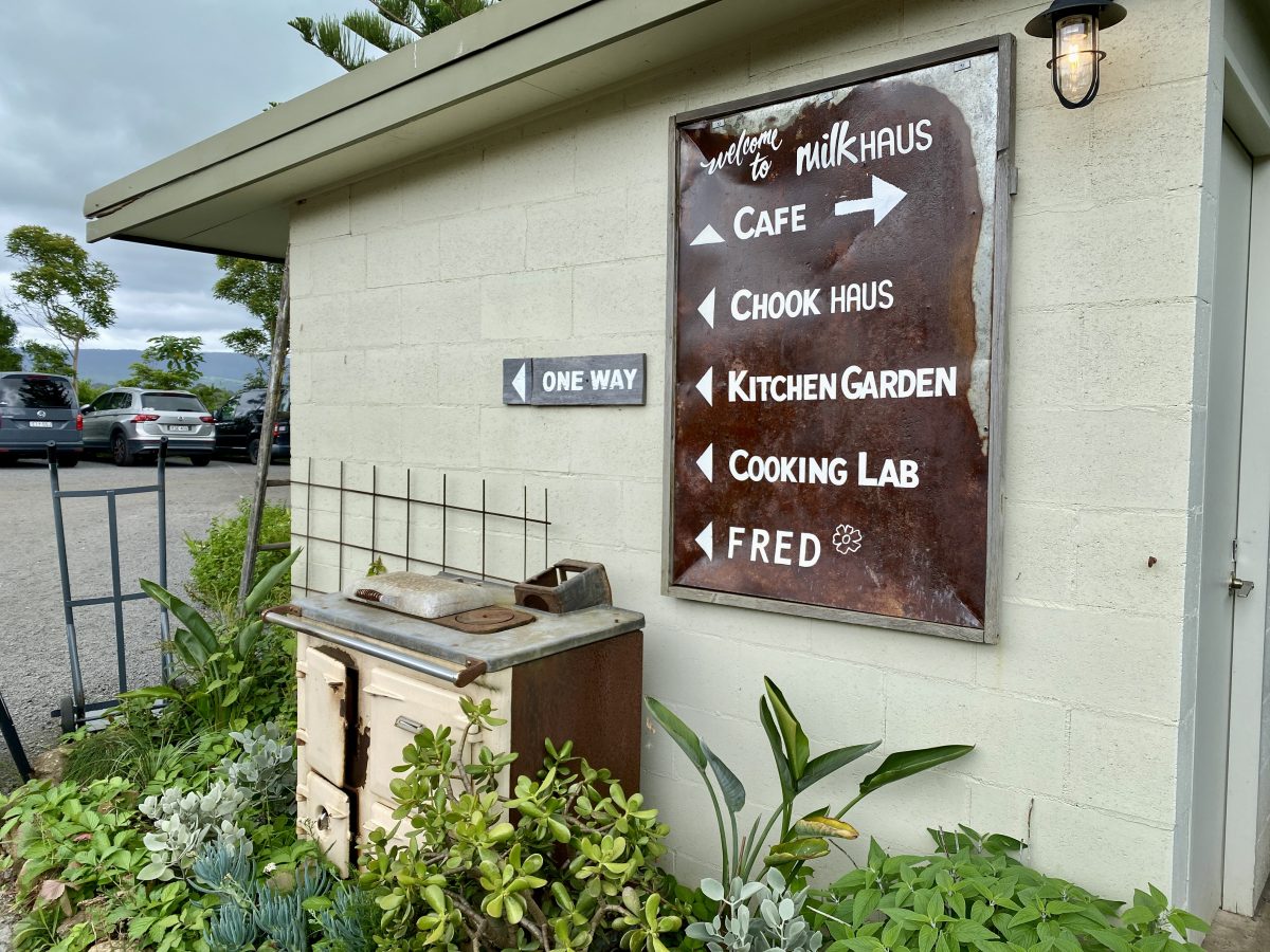 A retro sign pointing towards the cafe, kitchen garden etc. with a garden bed below